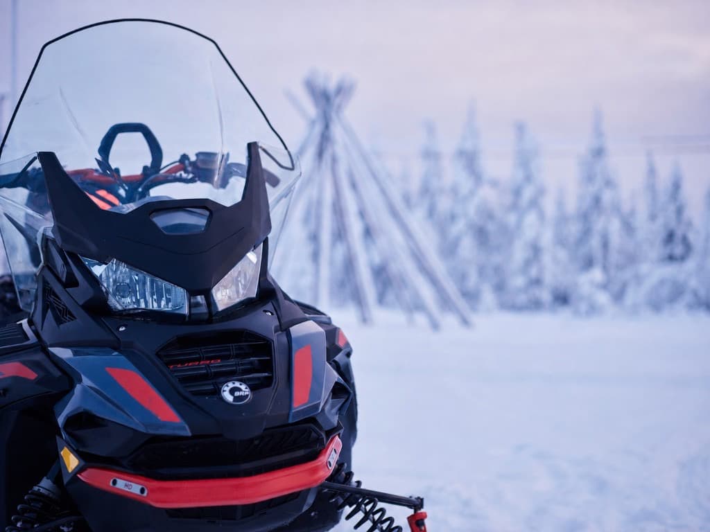 Snowmobile in pastel winter light with a Lappish tepee behind