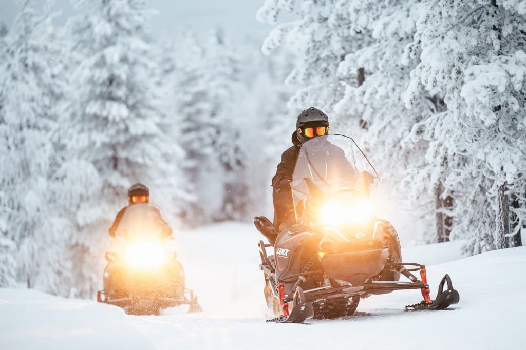 Snowmobiles weaving through the snow-covered forest